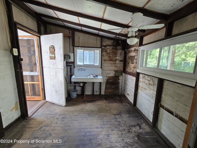 bathroom with hardwood / wood-style floors, wood walls, lofted ceiling, and sink