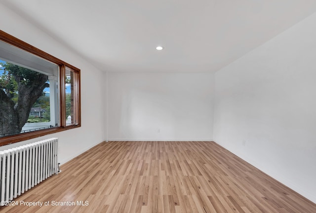 spare room with light wood-type flooring and radiator