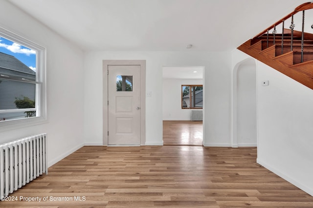 entryway featuring a healthy amount of sunlight, radiator heating unit, and light hardwood / wood-style floors