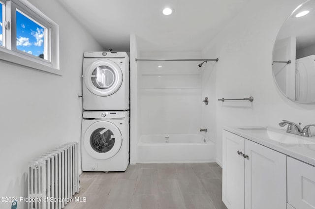 laundry room featuring radiator, sink, and stacked washer / drying machine