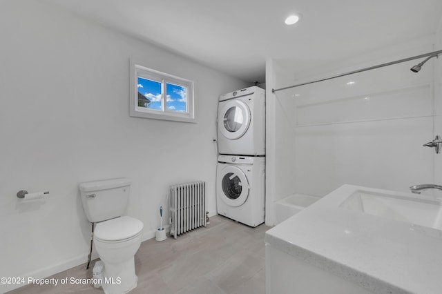 clothes washing area featuring radiator, sink, and stacked washing maching and dryer