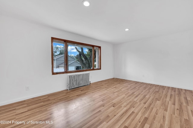 unfurnished room with light hardwood / wood-style flooring and radiator