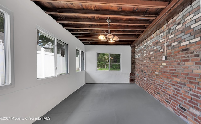 unfurnished sunroom with beamed ceiling, a healthy amount of sunlight, wood ceiling, and a chandelier