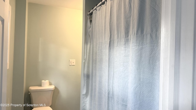 bathroom featuring a shower with curtain and toilet