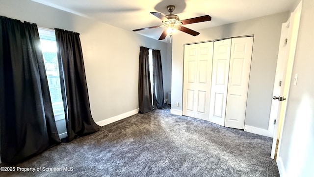 unfurnished bedroom with ceiling fan, dark carpet, and a closet