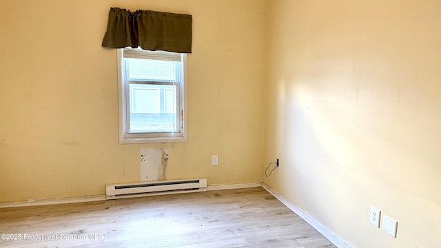 spare room featuring baseboard heating and light hardwood / wood-style floors