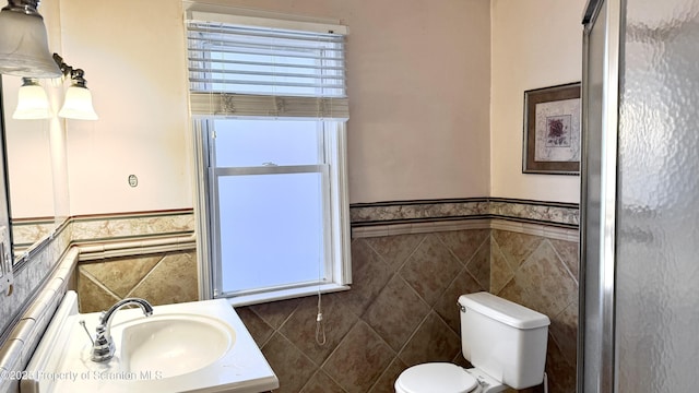 bathroom featuring vanity, toilet, and tile walls