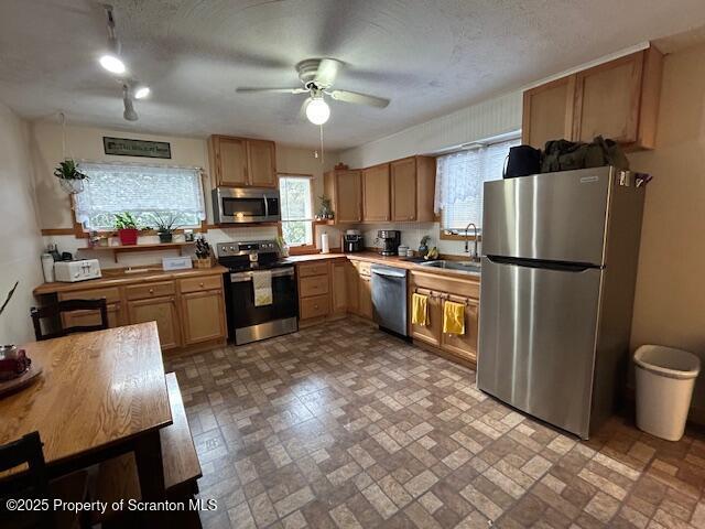 kitchen featuring ceiling fan, stainless steel appliances, sink, and a textured ceiling