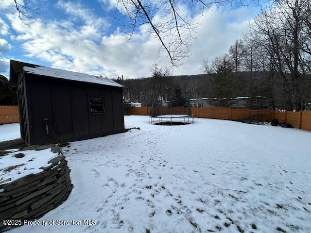 yard layered in snow with a trampoline