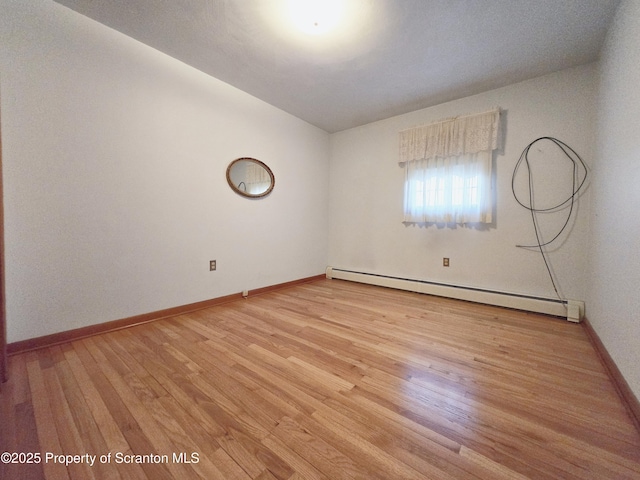 empty room featuring light wood-style flooring, baseboard heating, and baseboards