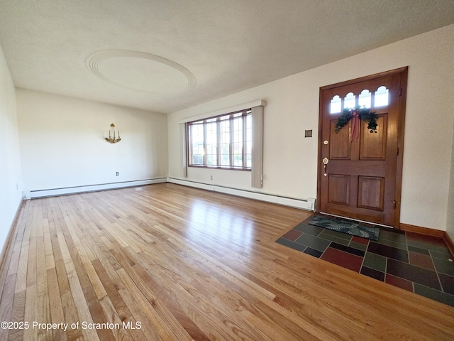 foyer with baseboard heating, baseboards, and wood finished floors