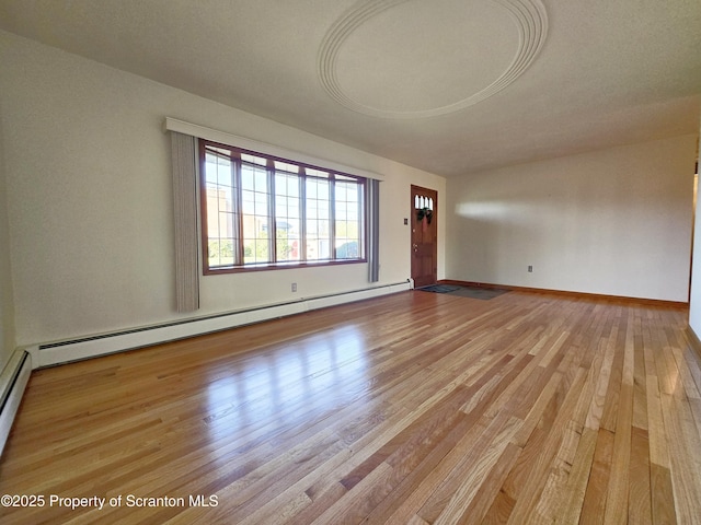 unfurnished living room with baseboard heating, light wood-style flooring, and baseboards