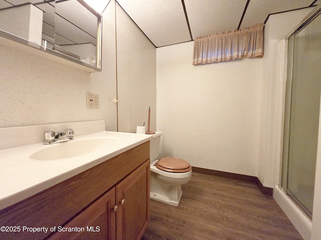 full bathroom featuring a shower stall, vanity, toilet, baseboards, and wood finished floors