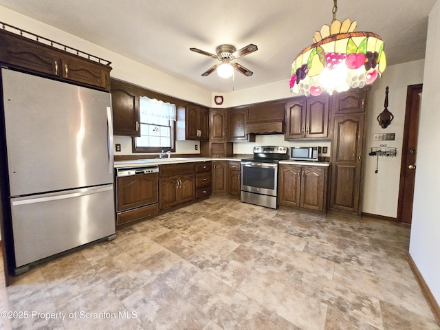 kitchen with a sink, stainless steel appliances, a ceiling fan, light countertops, and dark brown cabinets