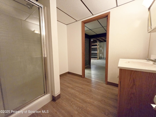 full bath featuring a stall shower, a paneled ceiling, wood finished floors, and vanity