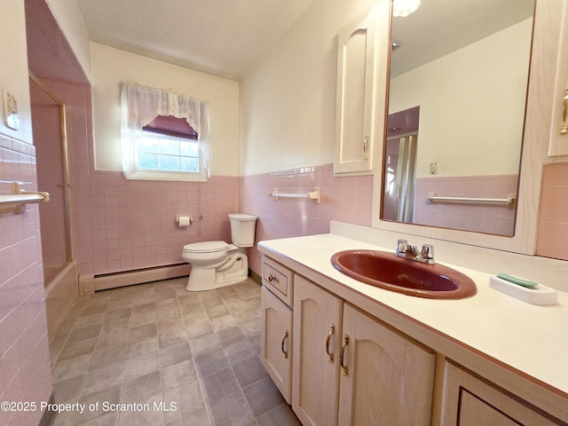 bathroom with wainscoting, baseboard heating, tile walls, toilet, and vanity