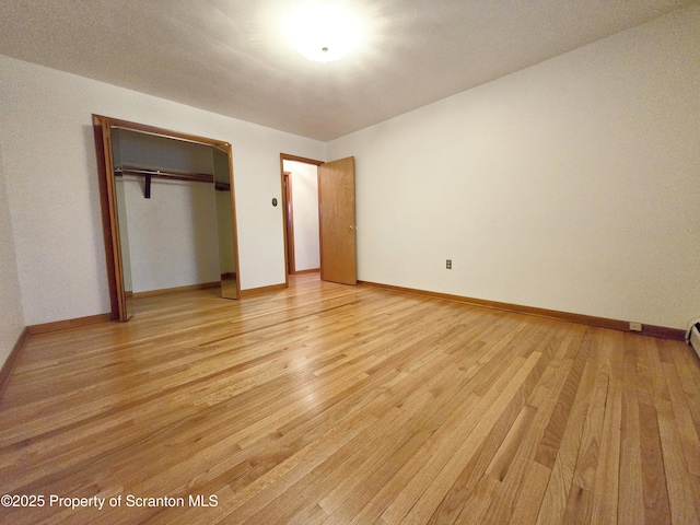 unfurnished bedroom featuring light wood finished floors, a closet, and baseboards