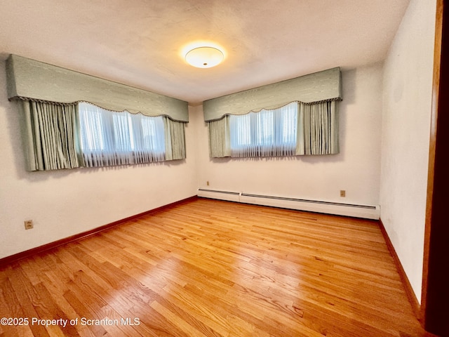 unfurnished room with baseboards, baseboard heating, and wood finished floors