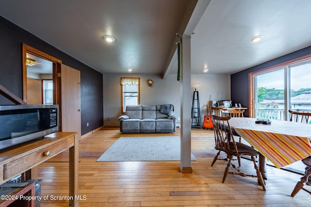 dining area featuring beamed ceiling and light wood-type flooring