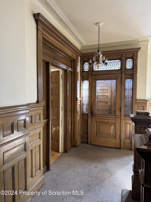 carpeted entrance foyer with a notable chandelier and crown molding