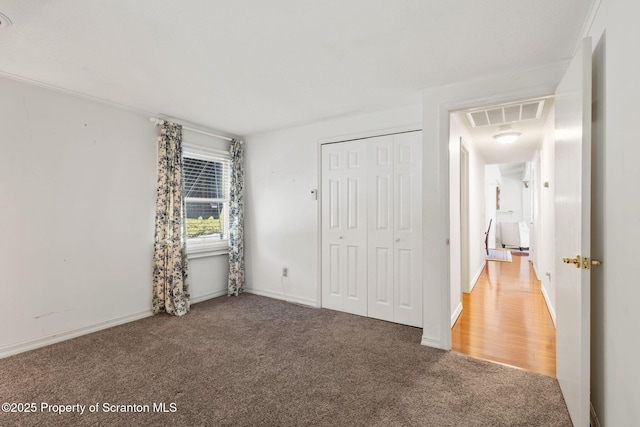 unfurnished bedroom with a closet, carpet flooring, baseboards, and visible vents