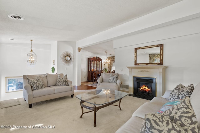 living area featuring visible vents, lofted ceiling, a notable chandelier, and a textured ceiling