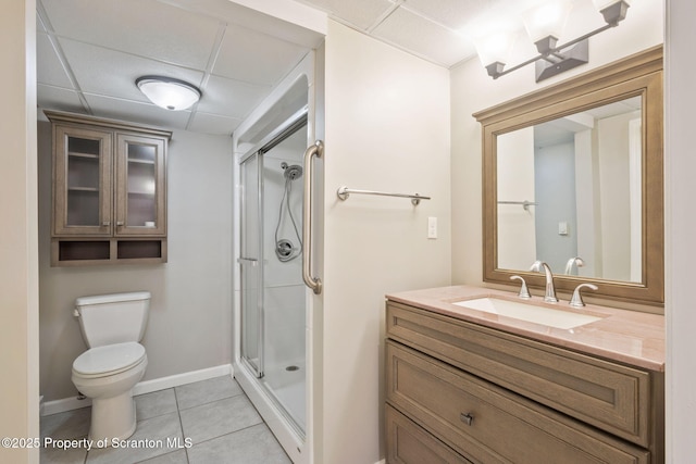 full bath featuring toilet, a stall shower, a drop ceiling, tile patterned flooring, and vanity