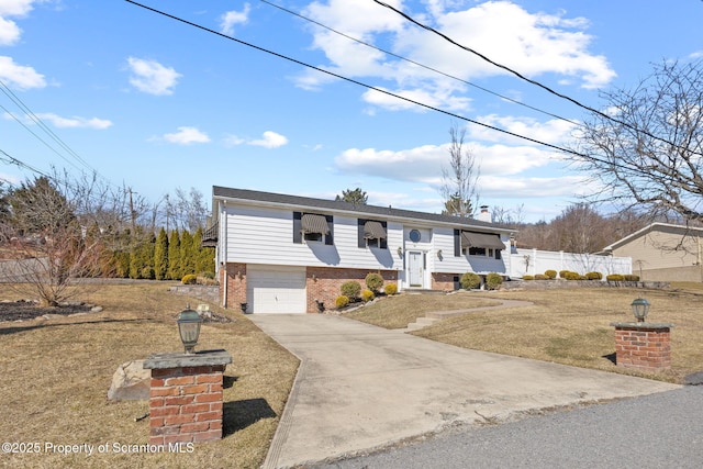 split foyer home with fence, concrete driveway, a garage, brick siding, and a chimney