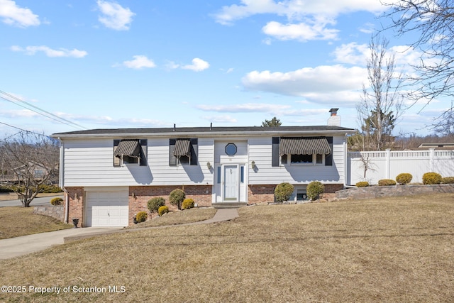 split foyer home featuring a front yard, brick siding, a chimney, and fence