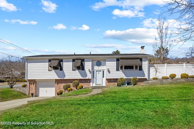 bi-level home with driveway, a front lawn, fence, brick siding, and a chimney