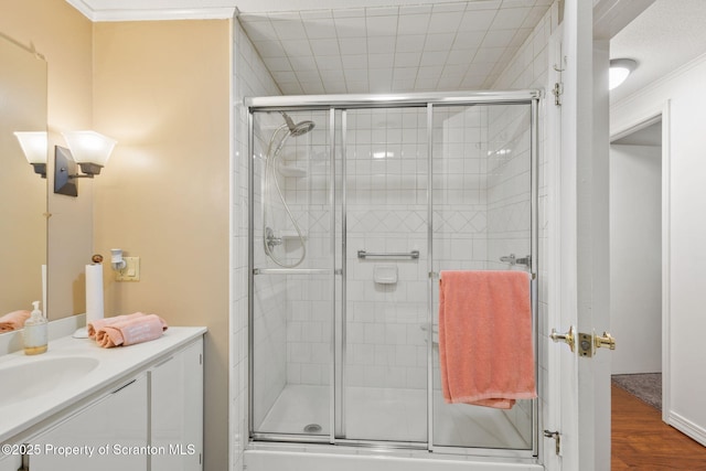 full bathroom featuring vanity, crown molding, wood finished floors, and a stall shower