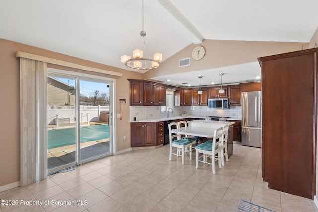 kitchen featuring lofted ceiling with beams, stainless steel appliances, light countertops, a notable chandelier, and backsplash