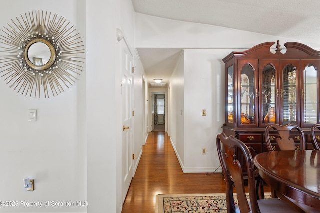 dining area with baseboards, lofted ceiling, and wood finished floors