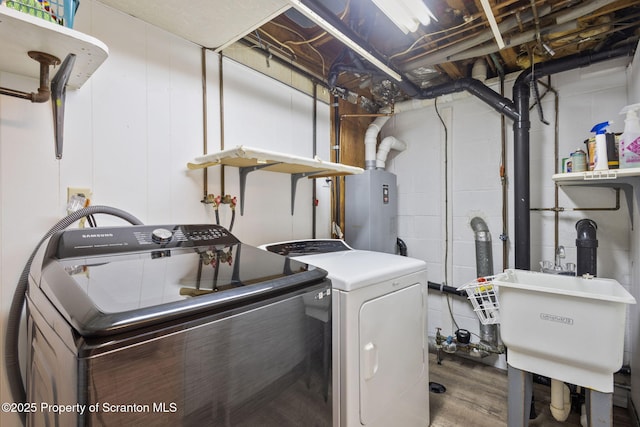 laundry area featuring a sink, wood finished floors, water heater, separate washer and dryer, and laundry area