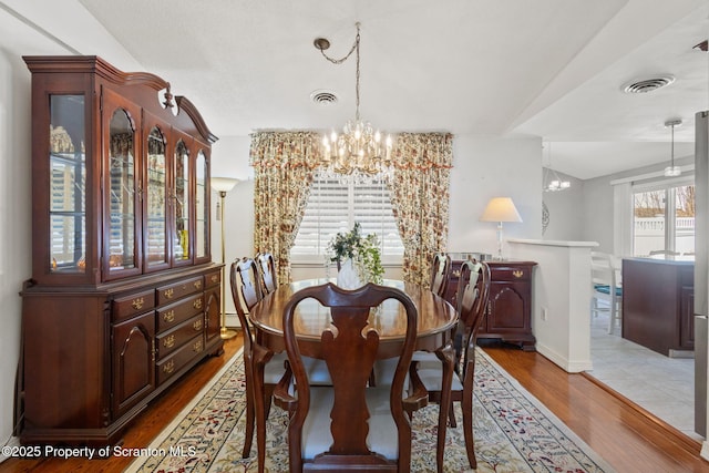 dining space featuring visible vents, baseboards, an inviting chandelier, and wood finished floors