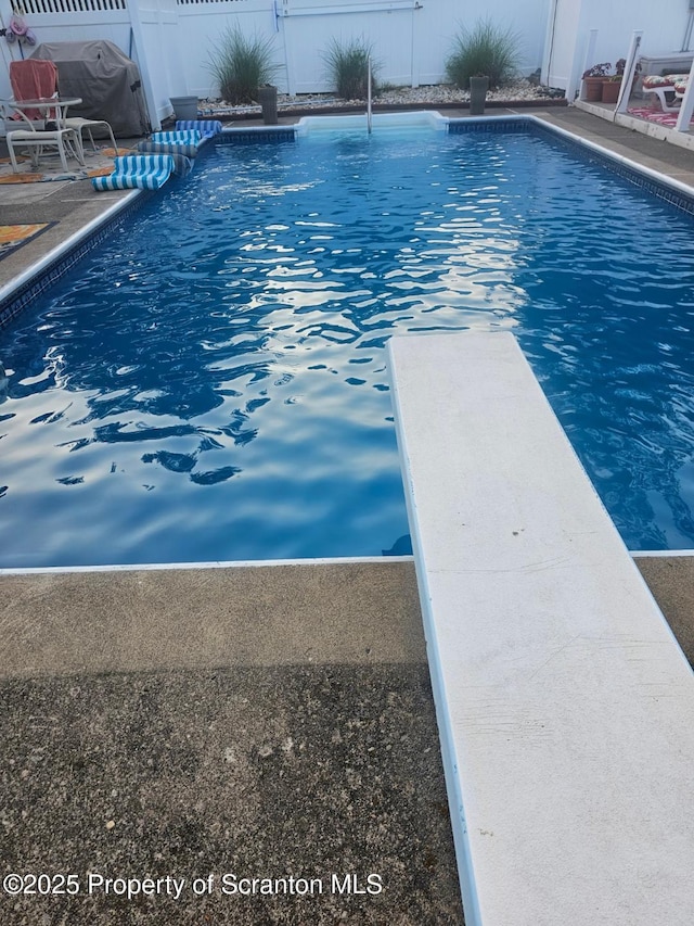 view of pool with a fenced in pool, a diving board, and fence