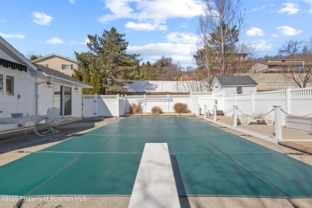 view of swimming pool featuring an outdoor structure, a fenced backyard, and a gate