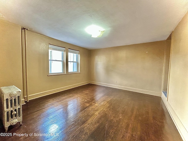 empty room with baseboards and dark wood finished floors