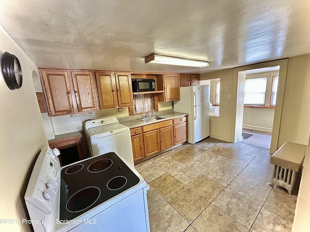kitchen featuring white appliances, brown cabinets, washer / dryer, and a sink