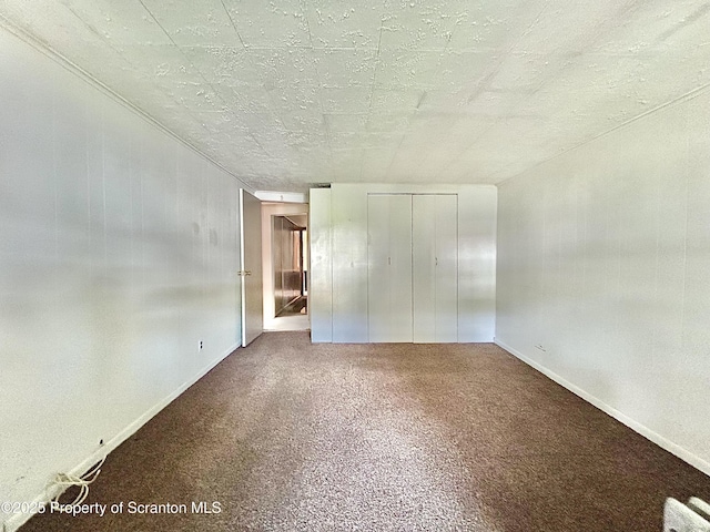 unfurnished bedroom featuring baseboards, carpet, and a closet