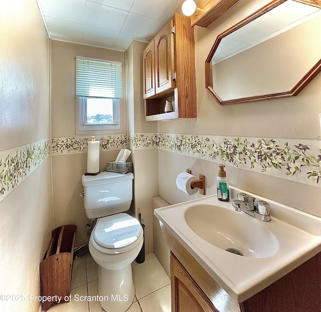 half bathroom with tile patterned flooring, vanity, toilet, a wainscoted wall, and tile walls