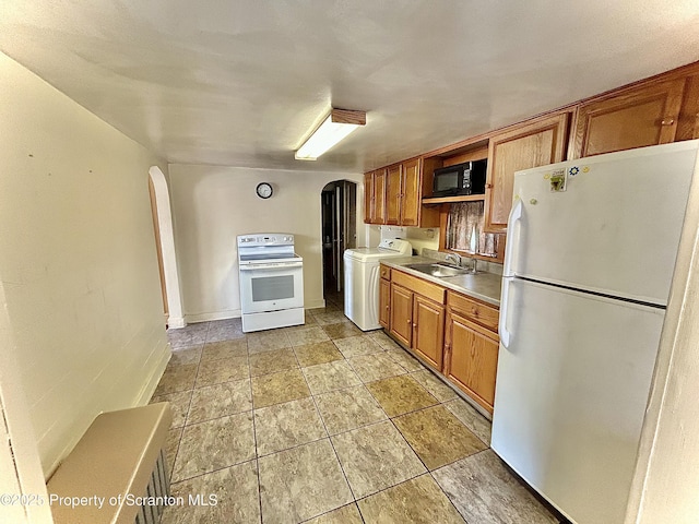 kitchen with a sink, white appliances, washer / clothes dryer, light countertops, and arched walkways