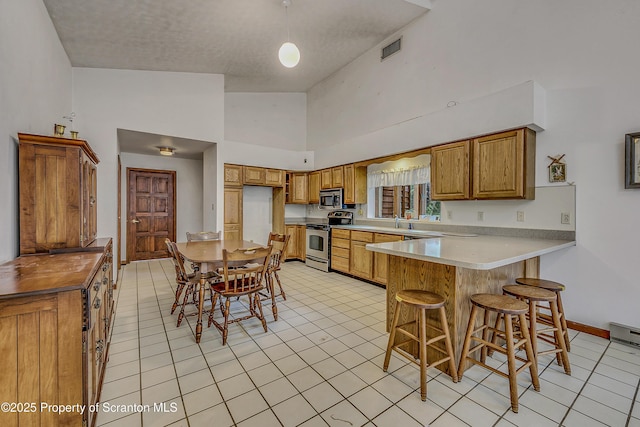 1300 Dundaff St, Dickson City, PA 18519 - kitchen with appliances with stainless steel finishes, a peninsula, brown cabinets, high vaulted ceiling, and light tile patterned flooring