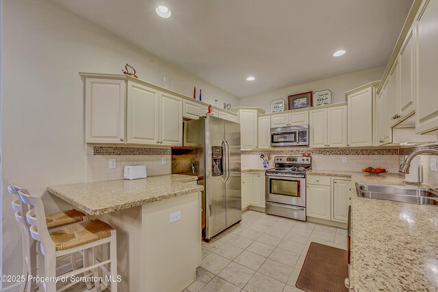 129 Wyndham Rd, South Abington Twp, PA 18411 - kitchen featuring stainless steel appliances, tasteful backsplash, light tile patterned floors, a breakfast bar area, and a peninsula