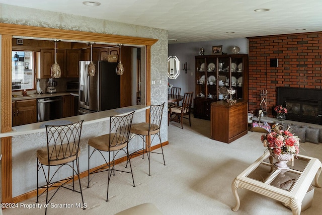 kitchen featuring sink, kitchen peninsula, light carpet, a fireplace, and appliances with stainless steel finishes