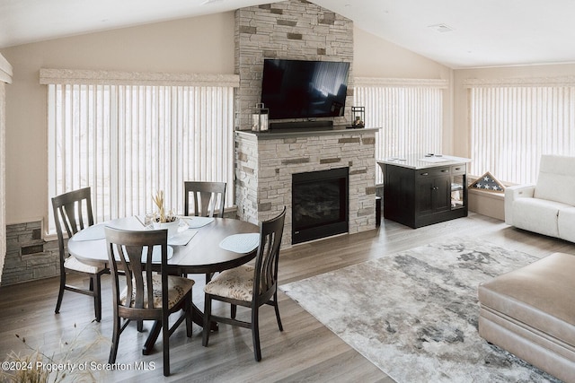 dining area with a fireplace, wood-type flooring, and lofted ceiling