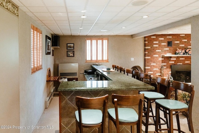 bar with a paneled ceiling, sink, and baseboard heating