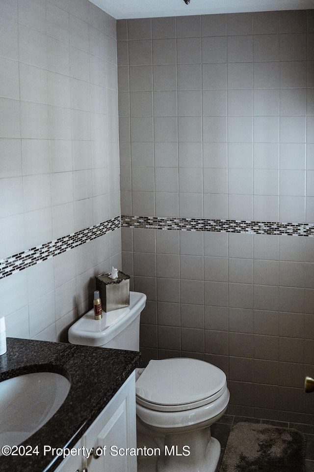 bathroom featuring vanity, tile walls, and toilet