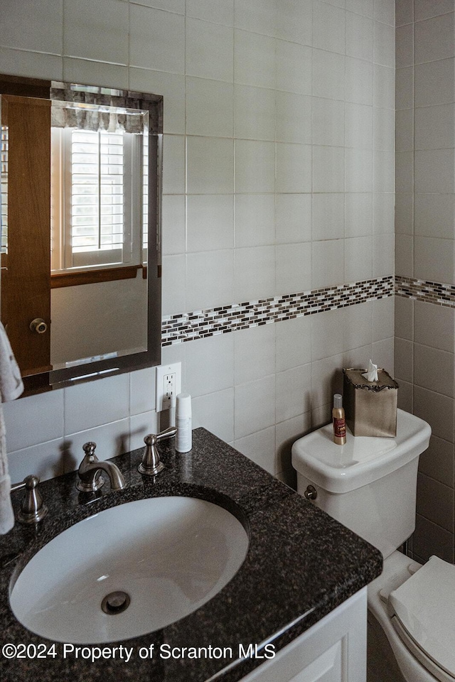 bathroom featuring vanity, backsplash, toilet, and tile walls