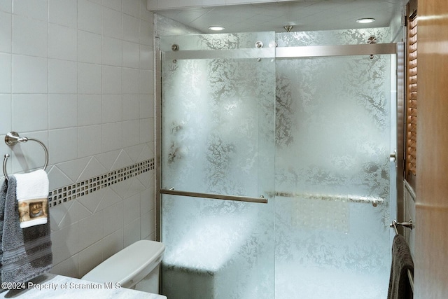 bathroom featuring toilet and a shower with shower door